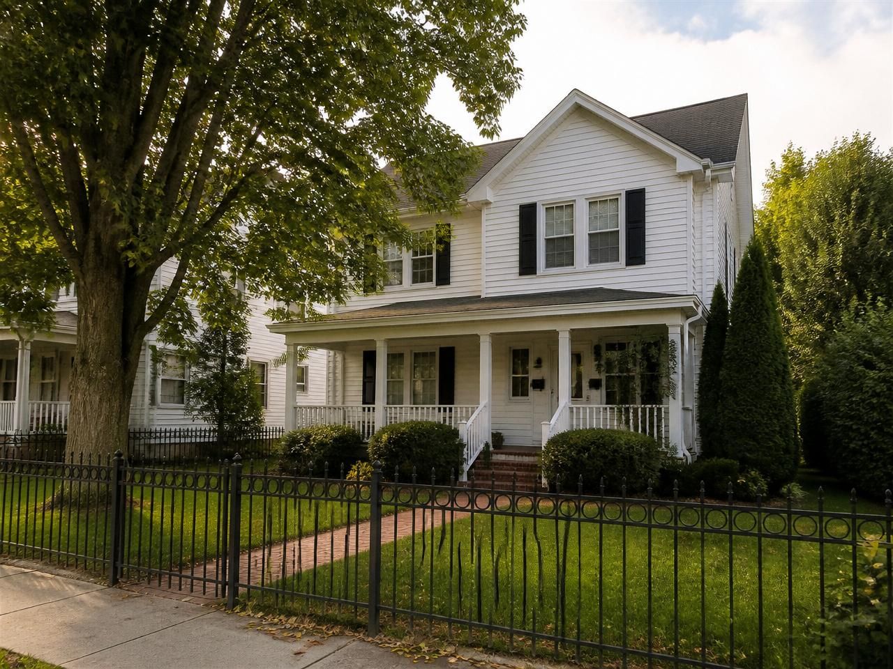 Classic white two-family colonial home with covered front porch and mature street tree in Hempstead, NY