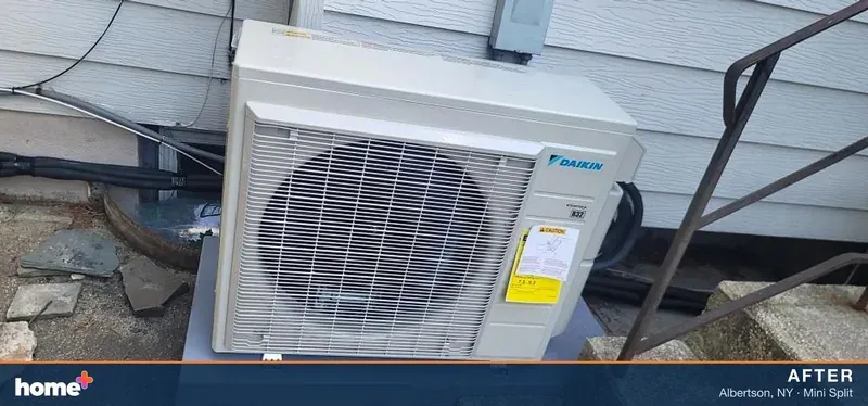 After: the new Daikin R-32 outdoor unit on a new equipment pad, with new black insulated line sets.