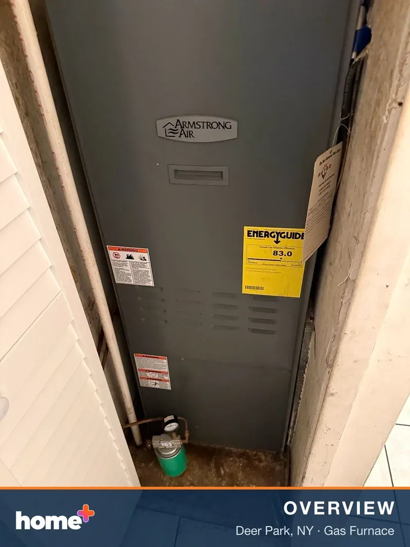 A gray Armstrong Air furnace unit is shown in a tight utility closet, with an EnergyGuide label visible on the front.