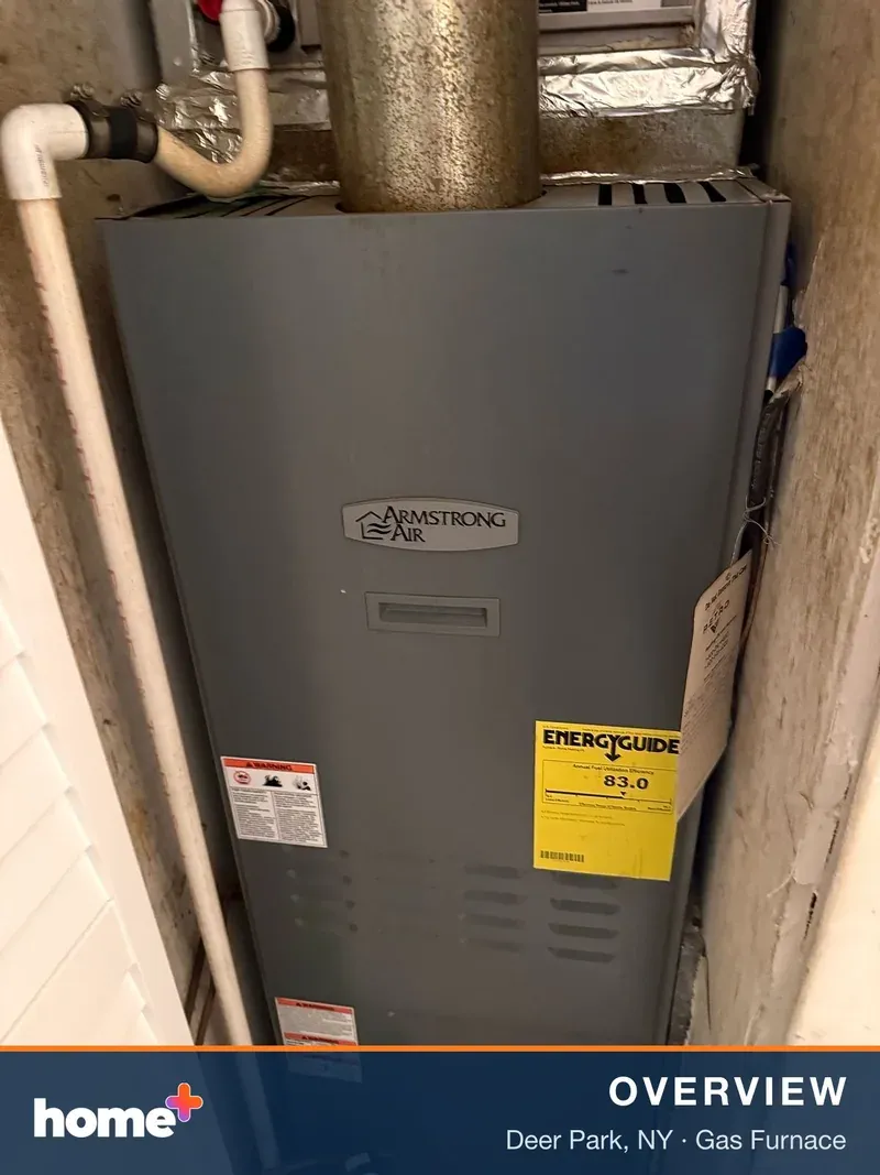 A gray Armstrong Air furnace unit is shown in a tight utility closet, with ductwork visible at the top.