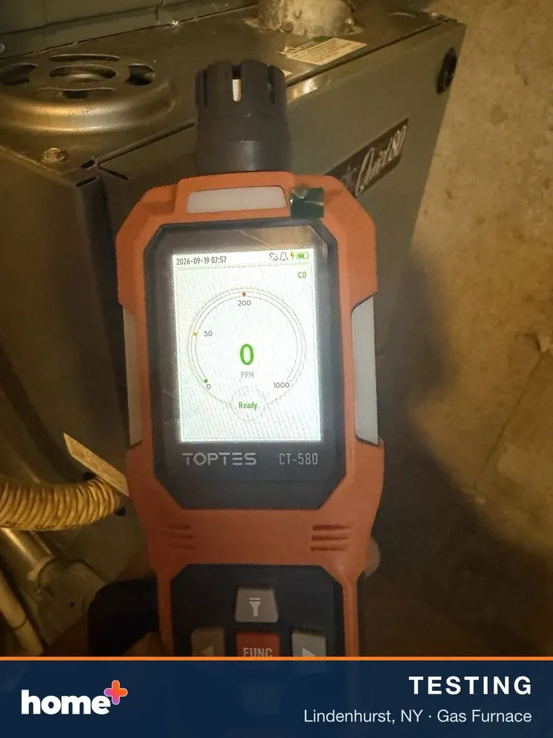 Carbon monoxide check at the furnace cabinet. The digital CO meter reads 0 PPM.