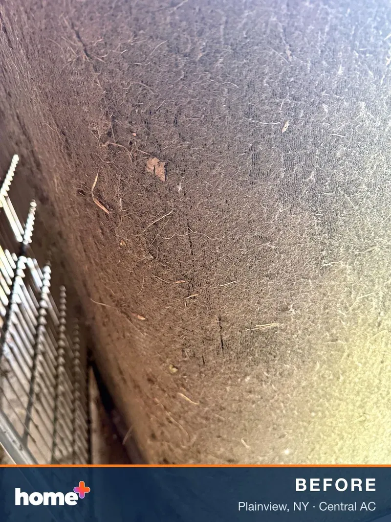 Extreme close-up of an outdoor air conditioner coil, showing the thick, matted accumulation of dirt and debris on its surface.