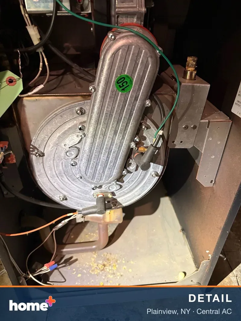 Detailed shot of the internal workings of an HVAC unit, focusing on a motor or blower component with a small green circular sticker.
