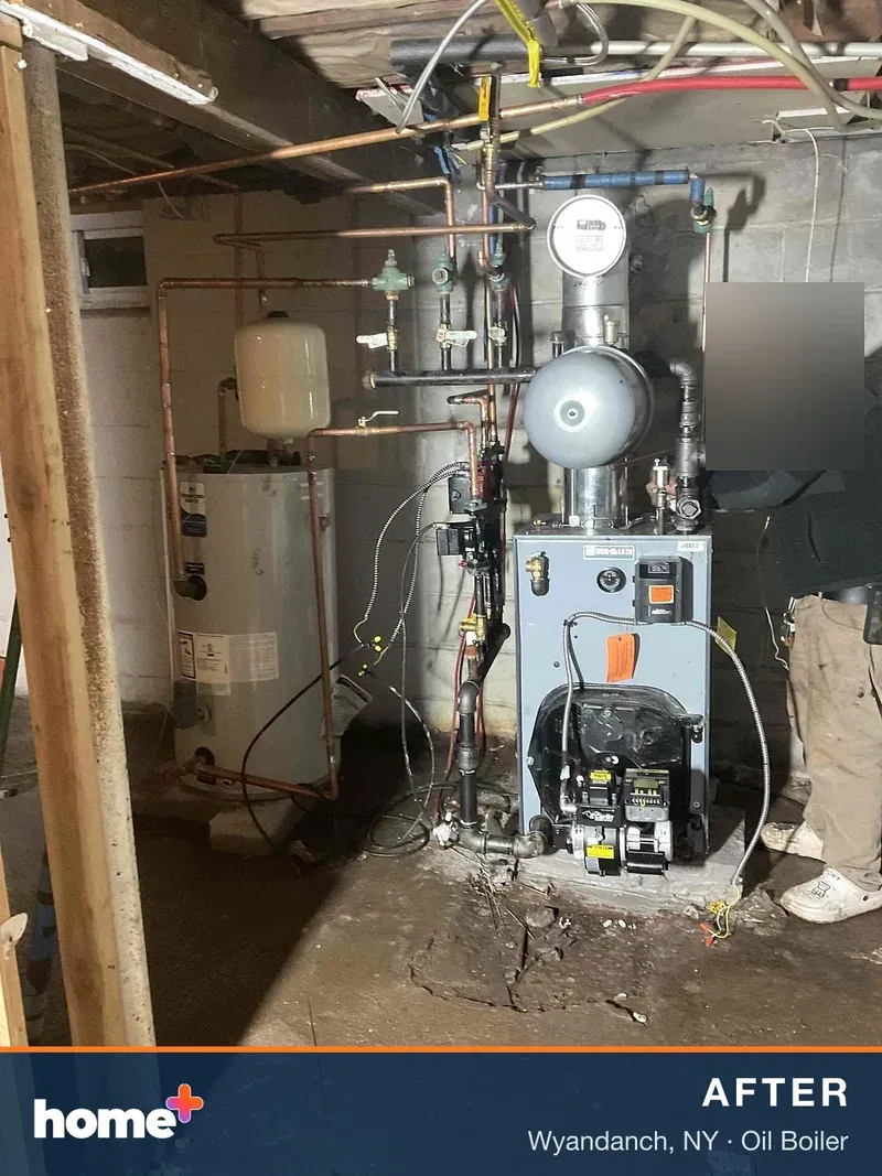 After: the new Weil-McLain oil boiler and Carlin burner in the same corner, reconnected to the heating zones and indirect tank during commissioning.